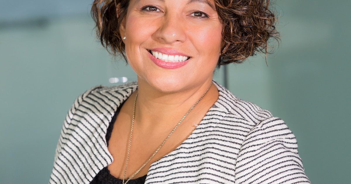 Professional woman in a warm, well-lit therapy environment representing human-centered mental health care