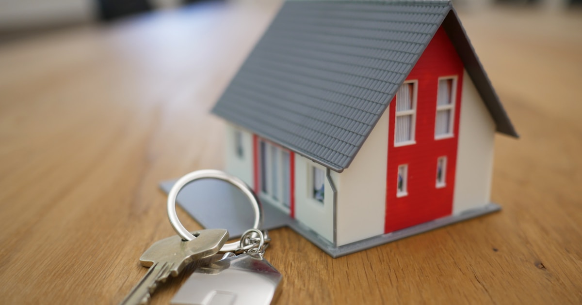Close-up of a small house model with keys on a table representing real estate technology
