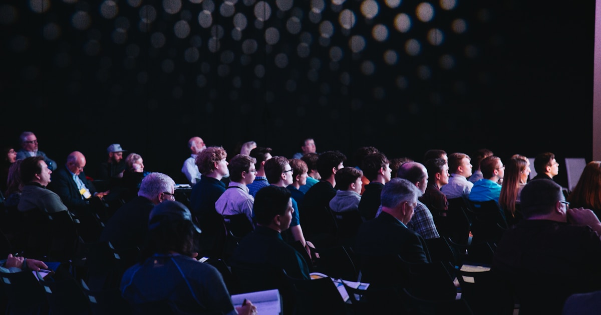 Large conference stage with audience and digital presentation screens